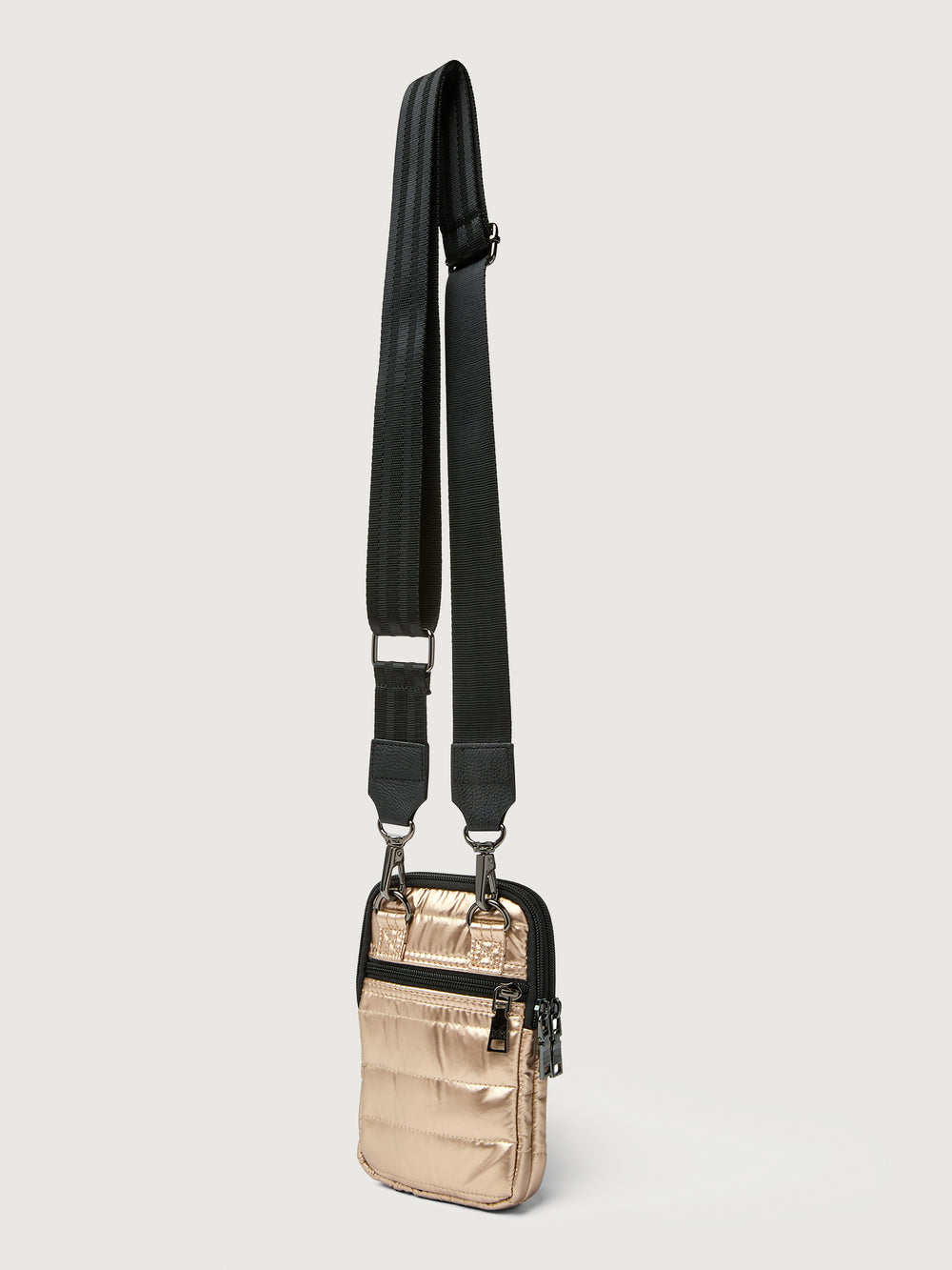 Gold crossbody bag with a black strap on a light gray background