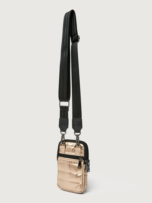 Gold crossbody bag with a black strap on a light gray background