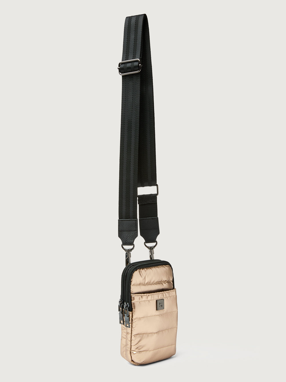 Beige crossbody bag with a black strap on a light gray background