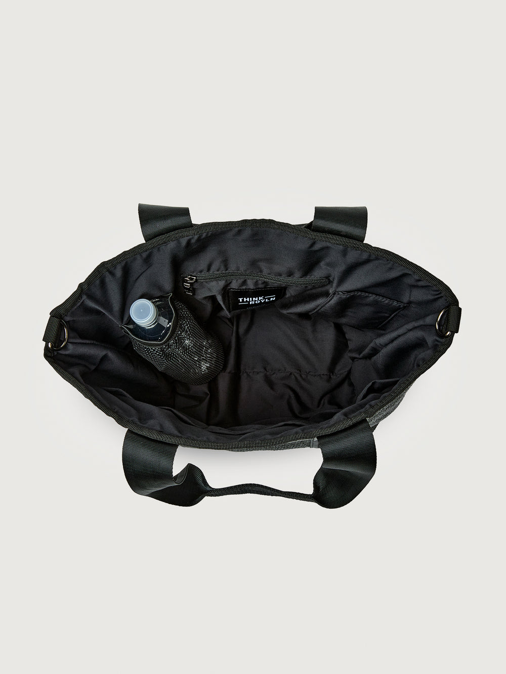 Interior view of Think Royln Capri black tote showing spacious lining, zip pocket, and side bottle holder.