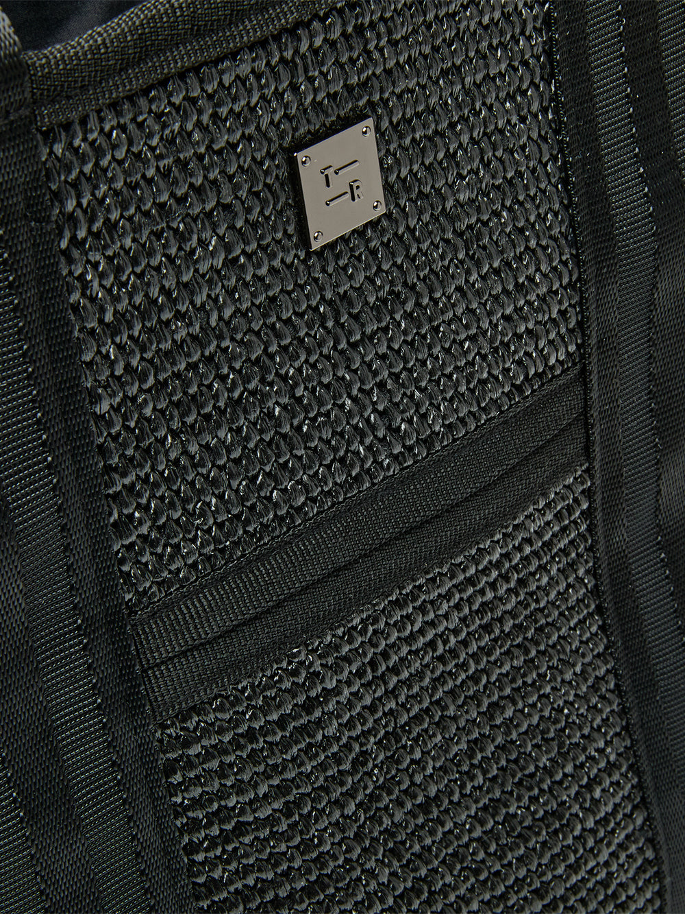 Close-up of Think Royln Capri woven black exterior with textured finish and silver logo plate.