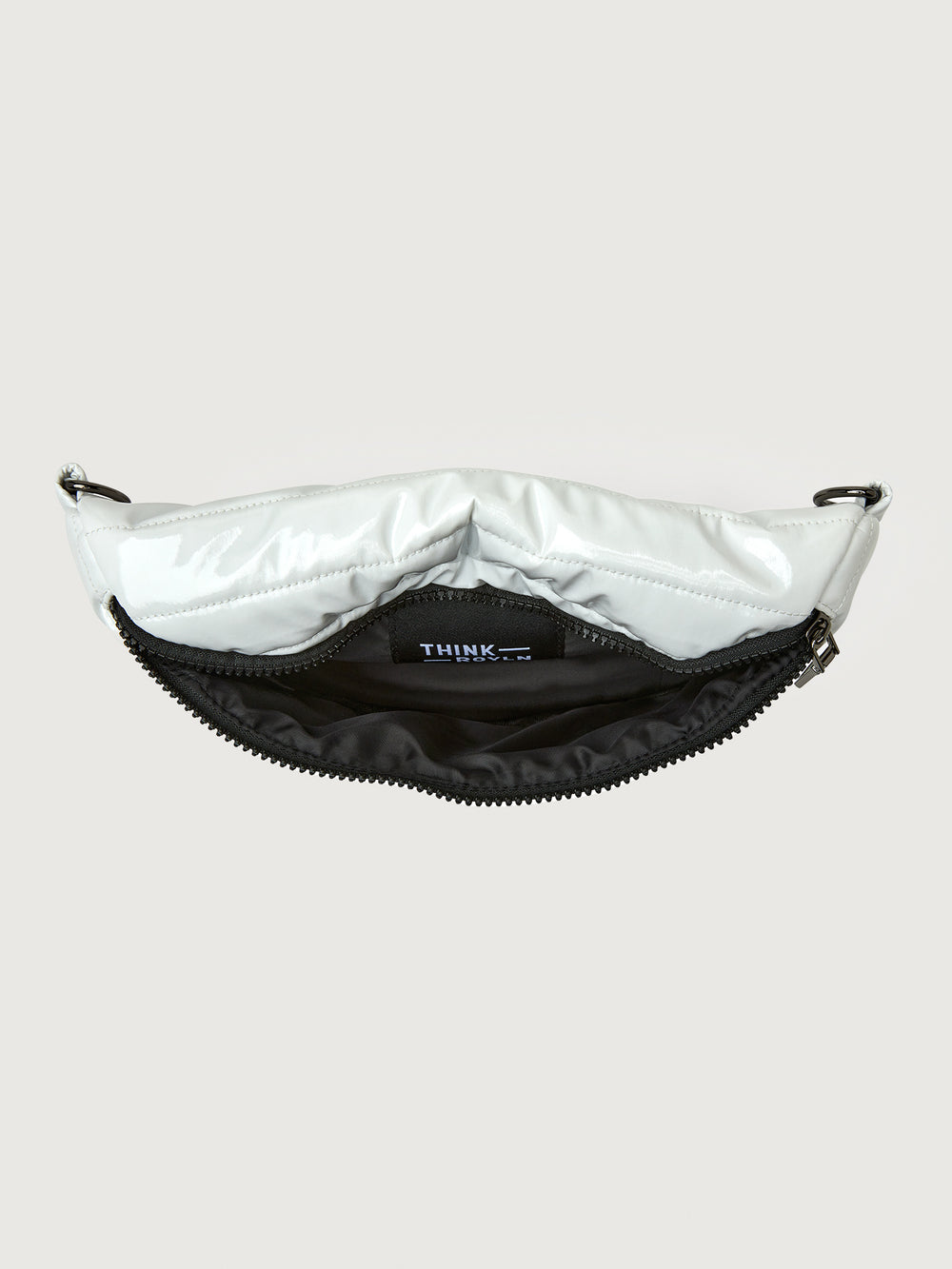 White patent leather bag with black hardware, featuring a half moon shape.