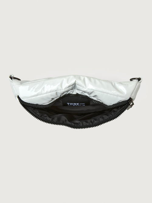 White patent leather bag with black hardware, featuring a half moon shape.