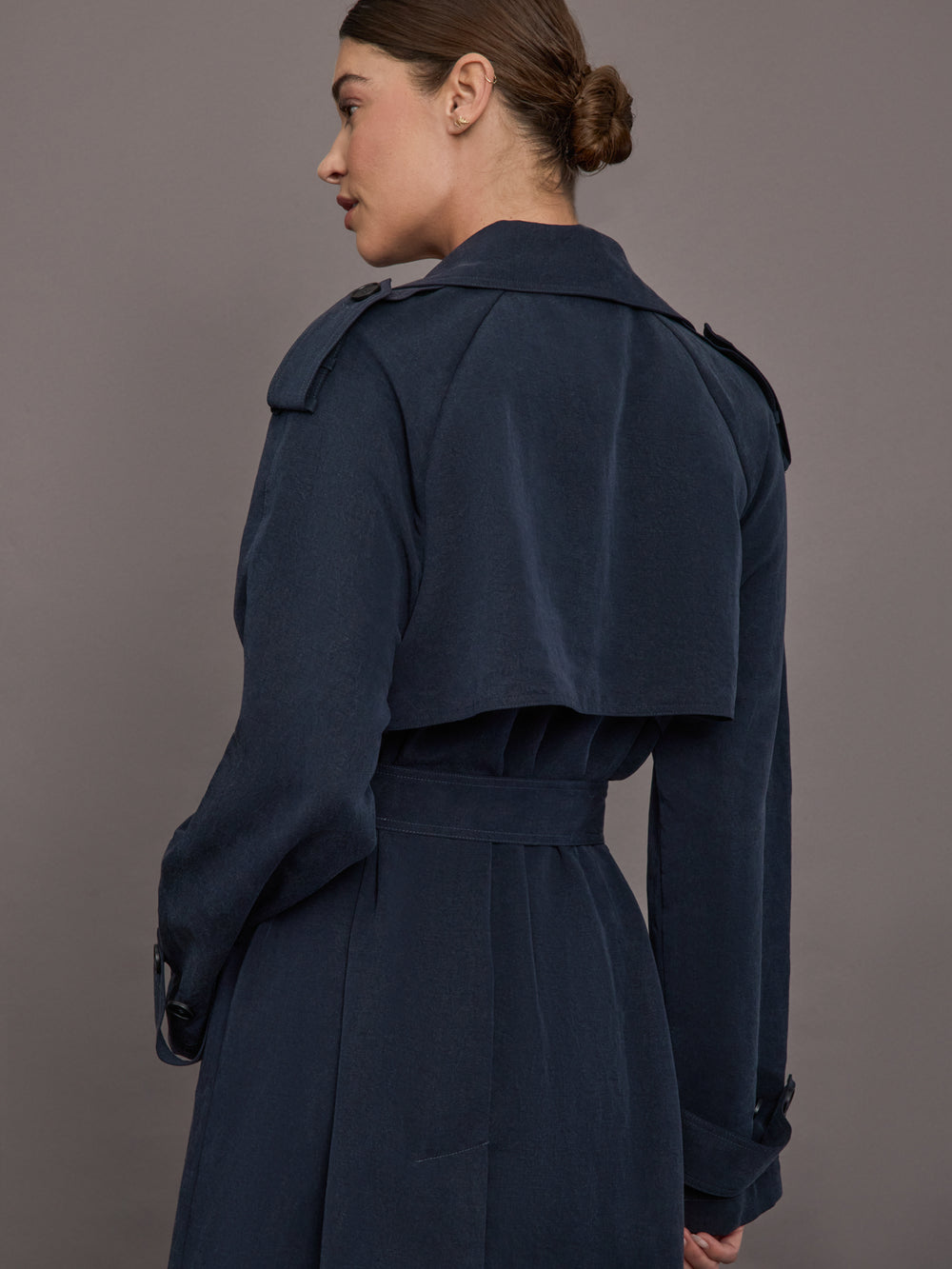 Model is wearing Elva Trench Coat in Navy, back view showing storm flap detail.
