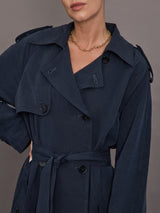 Model is wearing Elva Trench Coat in Navy, close up of lapel and button detailing.