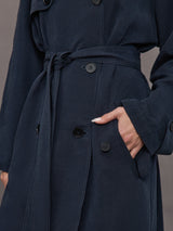 Model is wearing Elva Trench Coat in Navy, close up of waist belt and pocket detail.