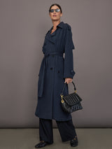 Model is wearing Elva Trench Coat in Navy, full body styling with handbag and sunglasses.