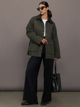 Model is wearing the utility barn jacket in dark olive, full body with sunglasses.