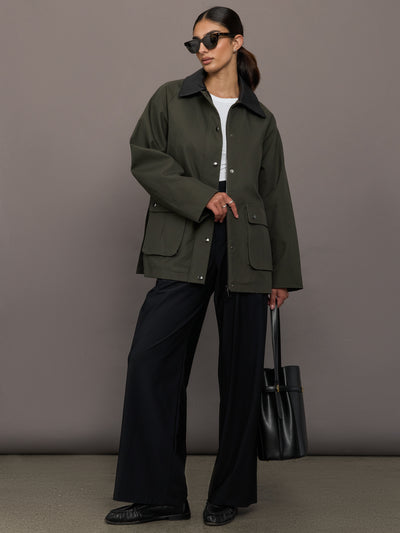 Model is wearing the utility barn jacket in dark olive, full body with sunglasses.