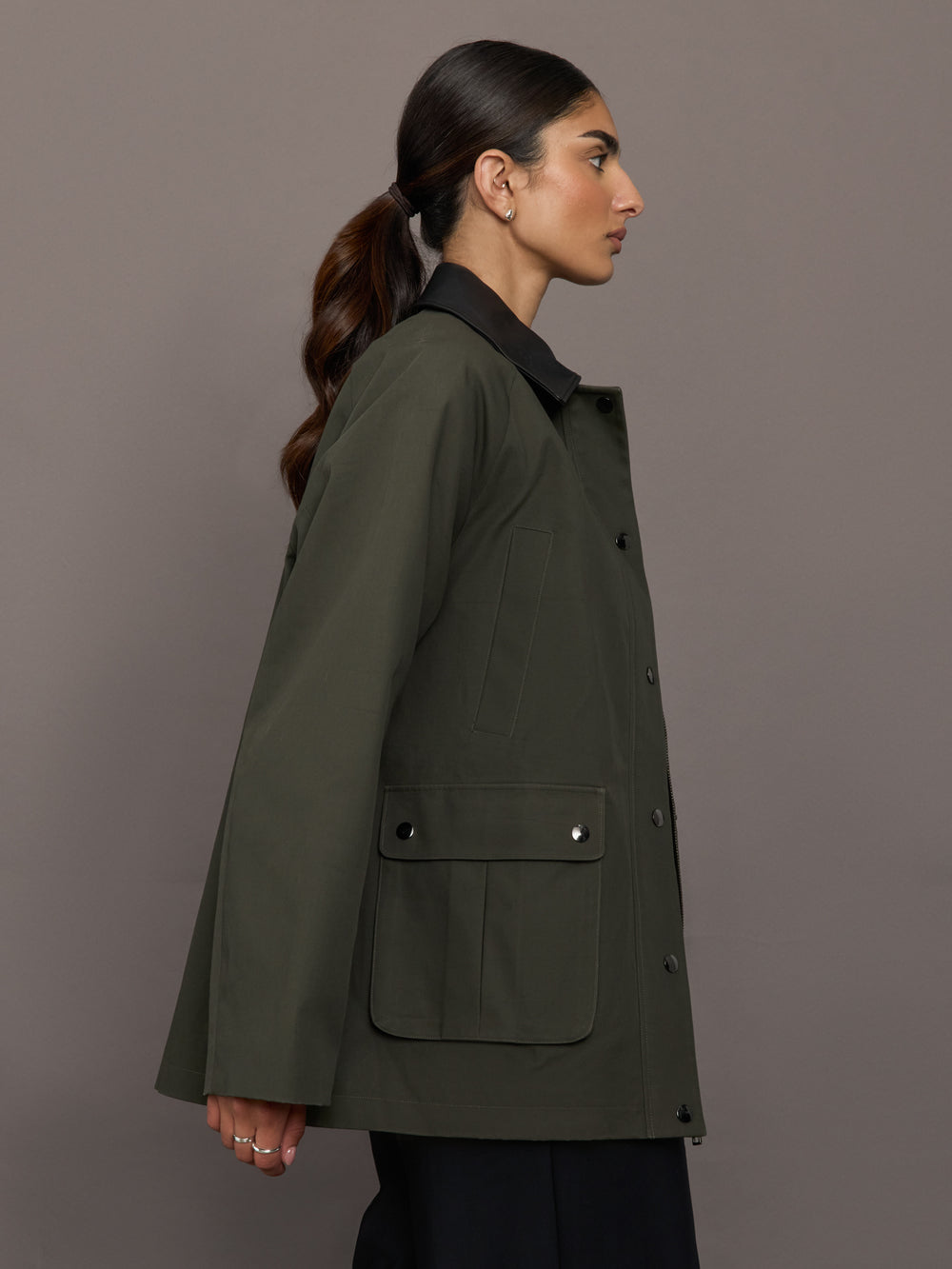 Model is wearing the utility barn jacket in dark olive, side view.