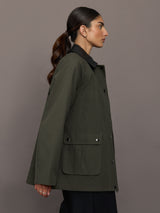 Model is wearing the utility barn jacket in dark olive, side view.