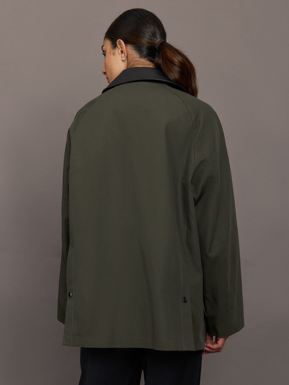 Model is wearing the utility barn jacket in dark olive, back view.