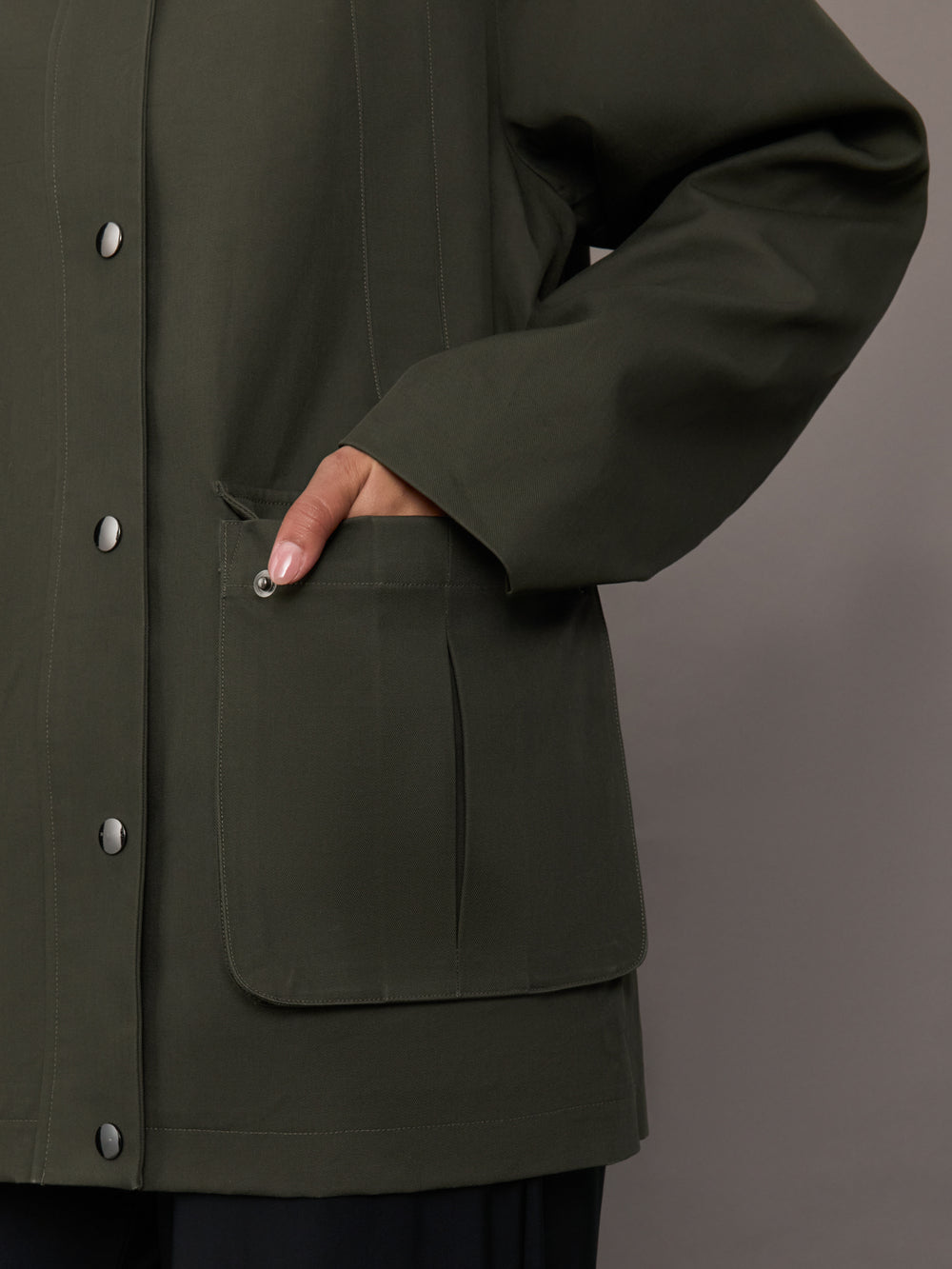 Close up of the utility barn jacket in dark olive, pocket detail.