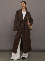 Model is wearing the belted maxi coat in brown with bag, full body.