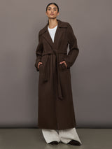 Model is wearing the belted maxi coat in brown, front view.