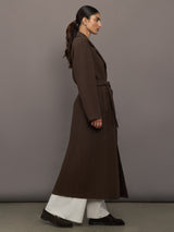 Model is wearing the belted maxi coat in brown, side view.