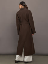 Model is wearing the belted maxi coat in brown, back view.