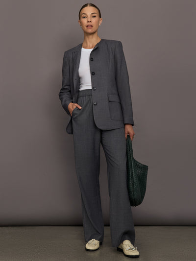Model is wearing the structured collarless blazer in grey with matching pant, full body.