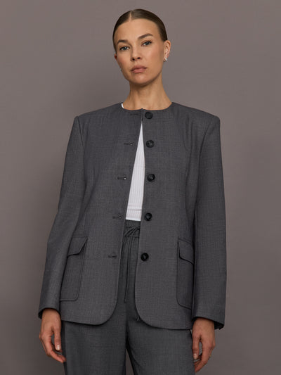 Model is wearing the structured collarless blazer in grey, front view.