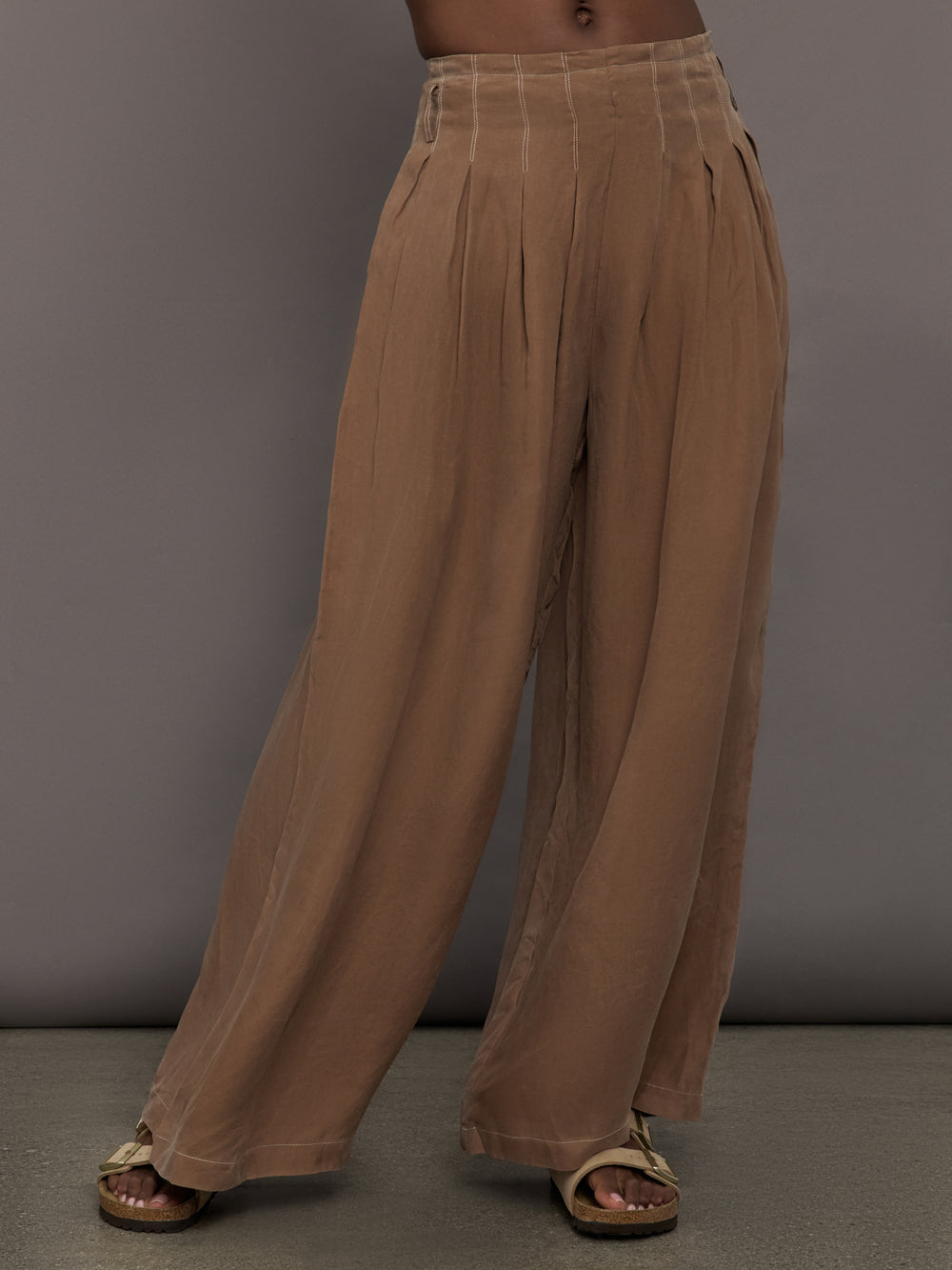 Model is wearing the Coconut cupro pleated wide leg pant, front view.