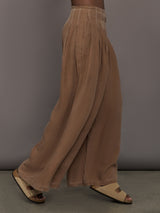 Model is wearing the Coconut cupro pleated wide leg pant, side walking view.