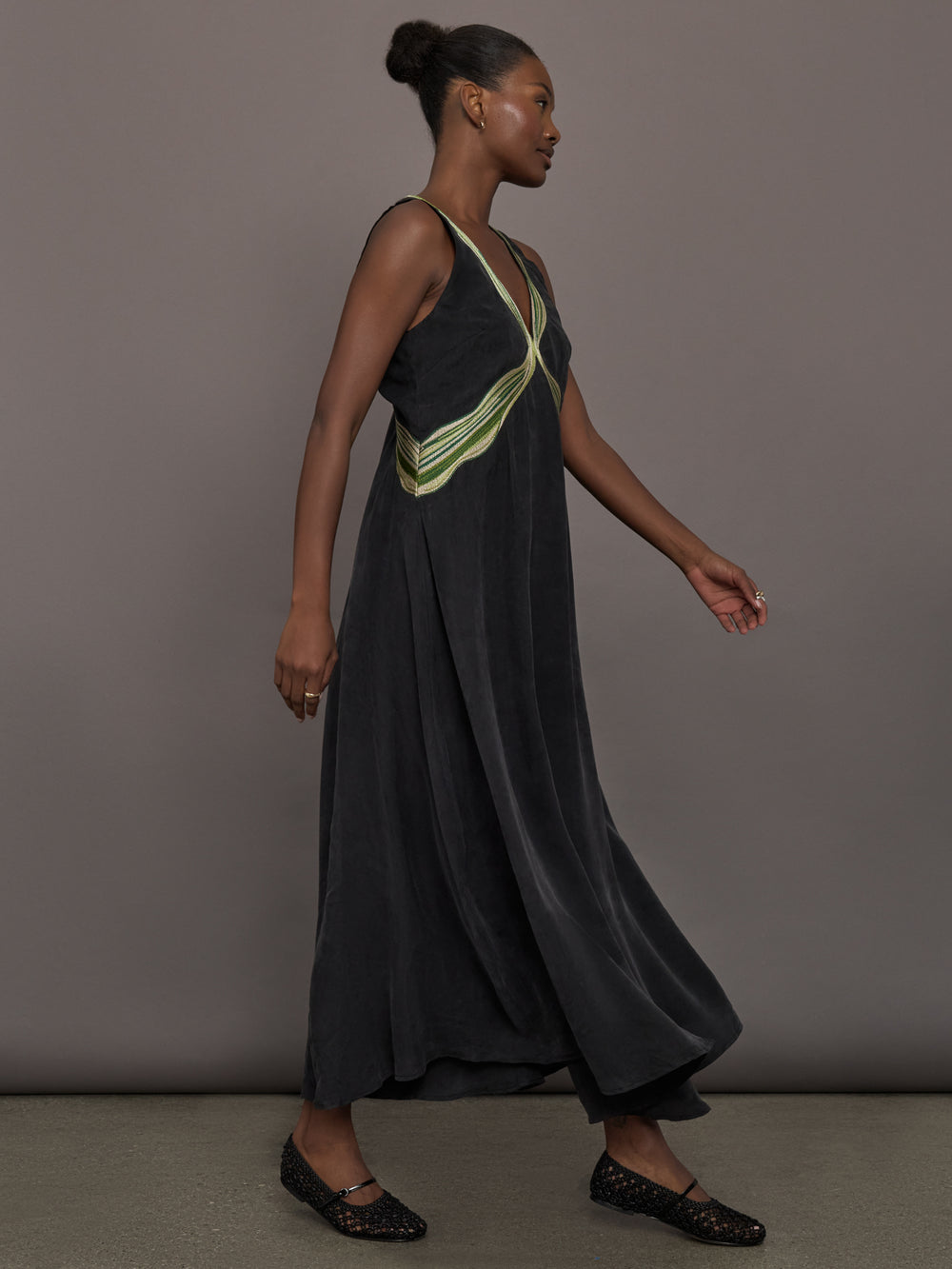 Model is wearing the Onyx embroidered cupro maxi dress, side walking view.