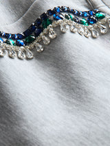 Close-up of grey sweatshirt fabric showing crystal jewel embellishment texture.