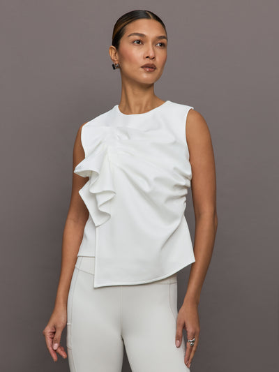 Model wears a sleeveless white top with ruffles. 