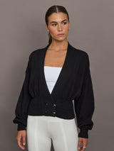 Model is wearing a black ribbed-waist cardigan with deep V-neckline, long sleeves, and button detail, front view.