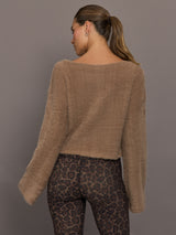 Model is wearing a taupe plush long-sleeve top with wide bell sleeves and a relaxed raw-edge hem, styled with leopard print leggings, back view.