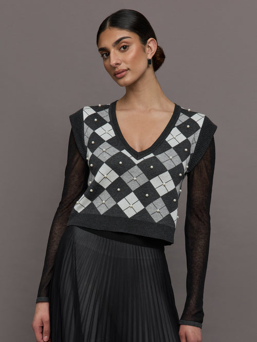 Model wears a gray argyle short sleeved V neck sweater with long black sheer sleeves. 