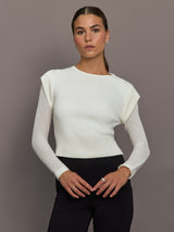 Model is wearing a white crew-neck sweater with sheer long sleeves and ribbed hem, front view.
