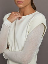 Close-up of white crew-neck sweater highlighting sheer mesh knit sleeves and ribbed shoulder detail, front view.