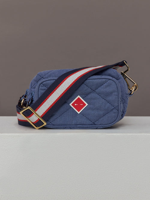 The Pacific Voyage Crossbody Bag in blue features a compact, structured design with a red, white, and blue adjustable strap.