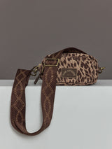 Crossbody bag with an animal print design, structured shape, adjustable strap, and zippered closure.