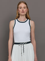 Model wears a white tank top with green trim, perfect for tennis. 