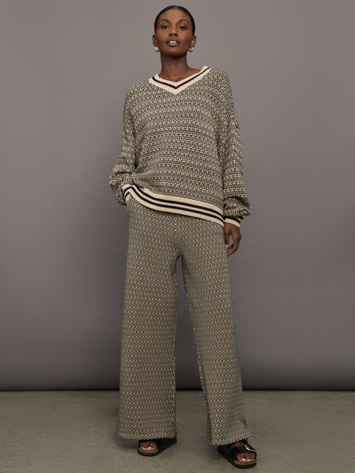 Model is wearing a black and white patterned v neck knit sweater.