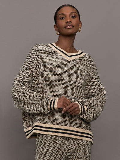 Model is wearing a black and white patterned v neck knit sweater.