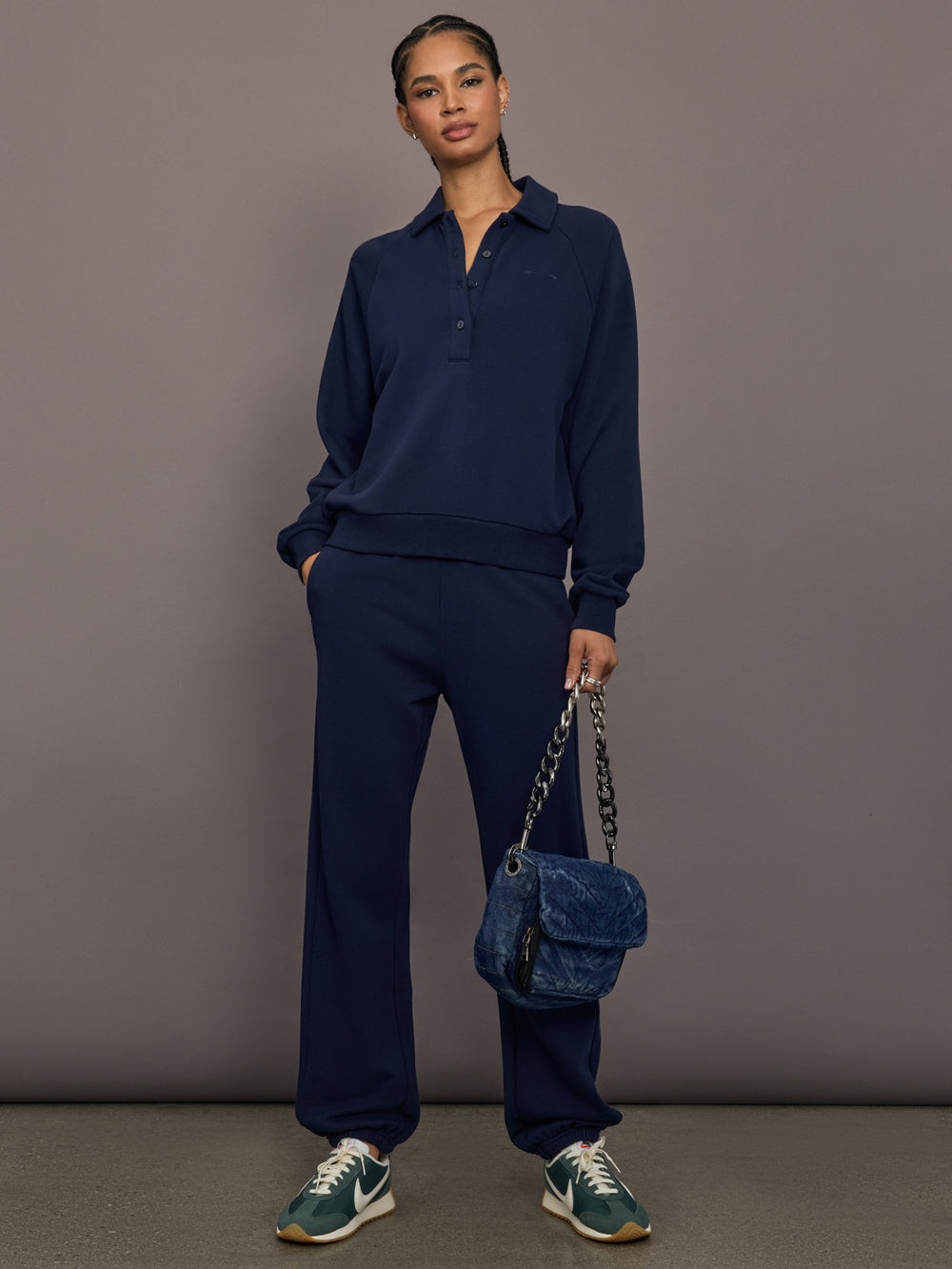 Model is wearing Collared Elle Polo in navy, full body view styled with track pants.