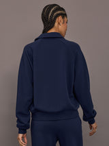 Model is wearing Collared Elle Polo in navy, back view with long sleeve silhouette.