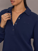 Model is wearing Collared Elle Polo in navy, close up of collar and embroidered logo.