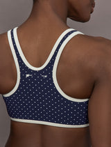 Model is wearing Spellbound Racerback Sports Bra in Polka Dot, back logo close-up.