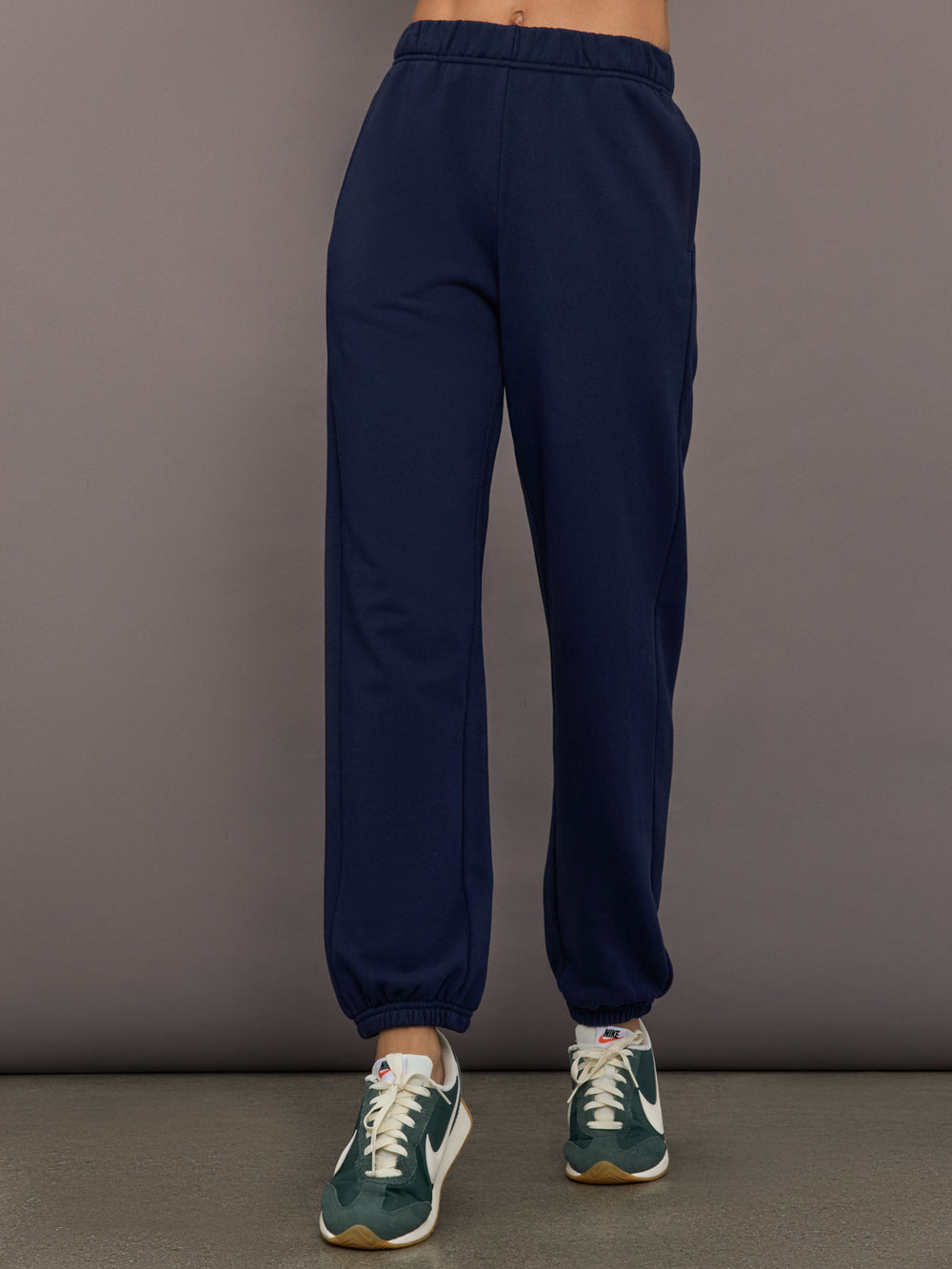 Model is wearing Harrison Track Pant in navy, front view.