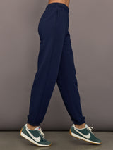 Model is wearing Harrison Track Pant in navy, side view.