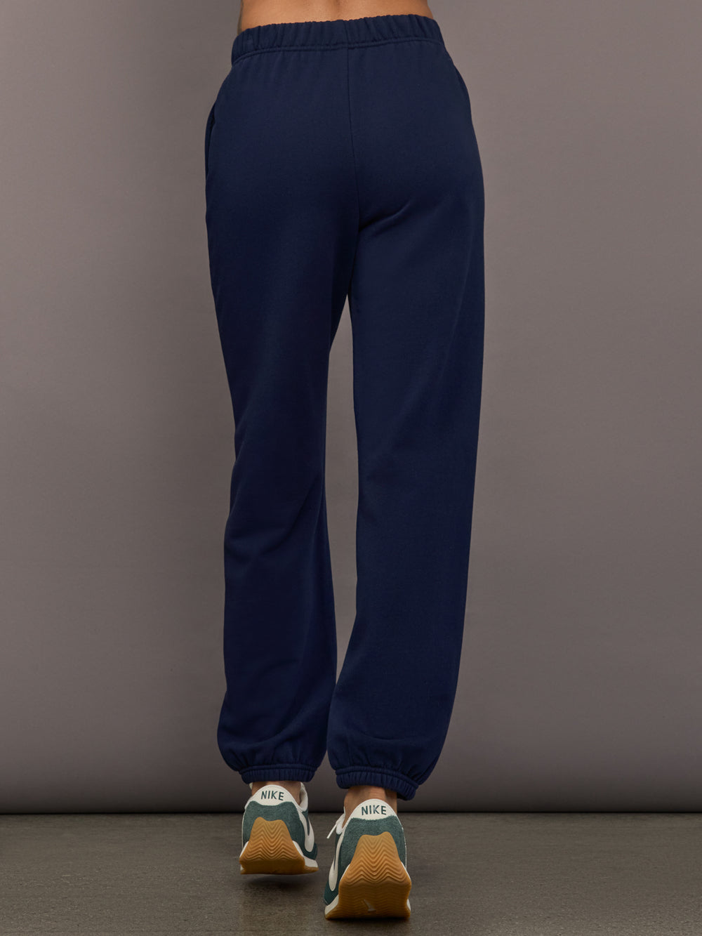 Model is wearing Harrison Track Pant in navy, back view.