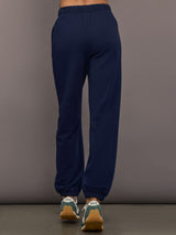 Model is wearing Harrison Track Pant in navy, back view.