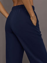 Model is wearing Harrison Track Pant in navy, close up of fabric and pocket detail.