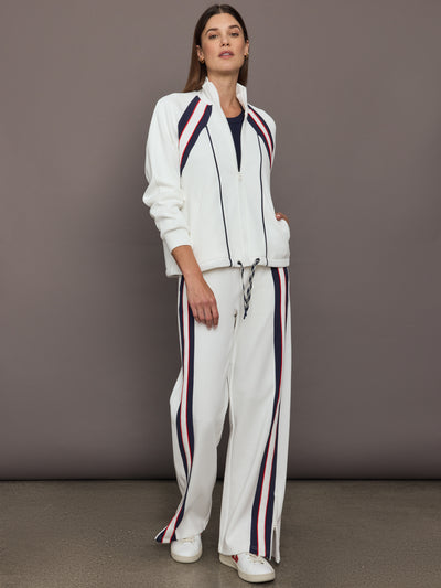 Model wears The Pacific Morgan Zip Up Jacket in white with a sleek, sporty design with a full front zipper, high collar, and navy and red detailing.