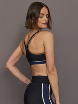 Model wears black racerback sports bra with a scoop neckline and brown, white and navy detailing.