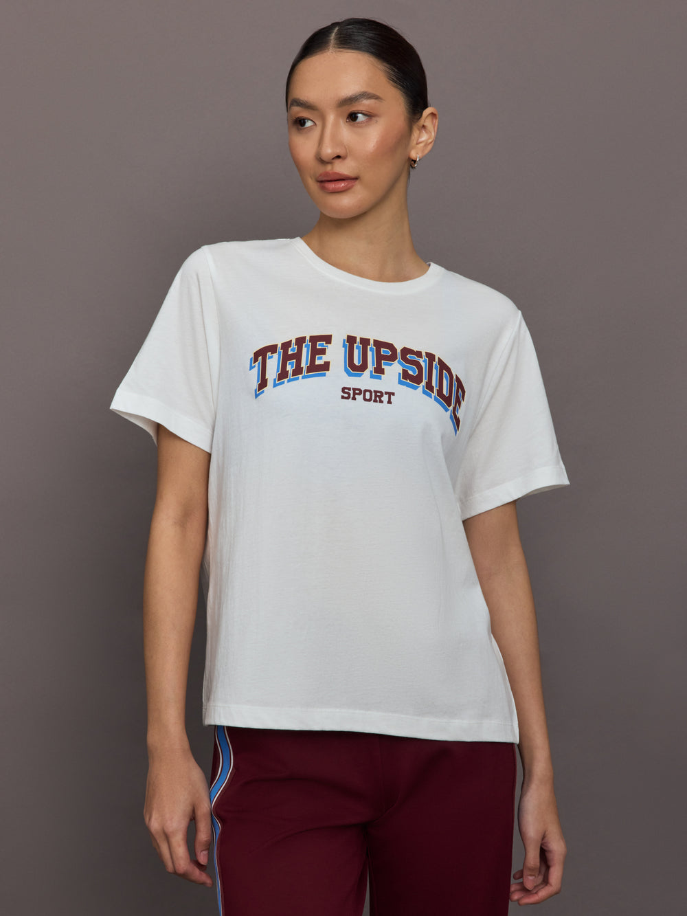 Person wearing a white t-shirt with 'The Upside Sport' text on a gray background